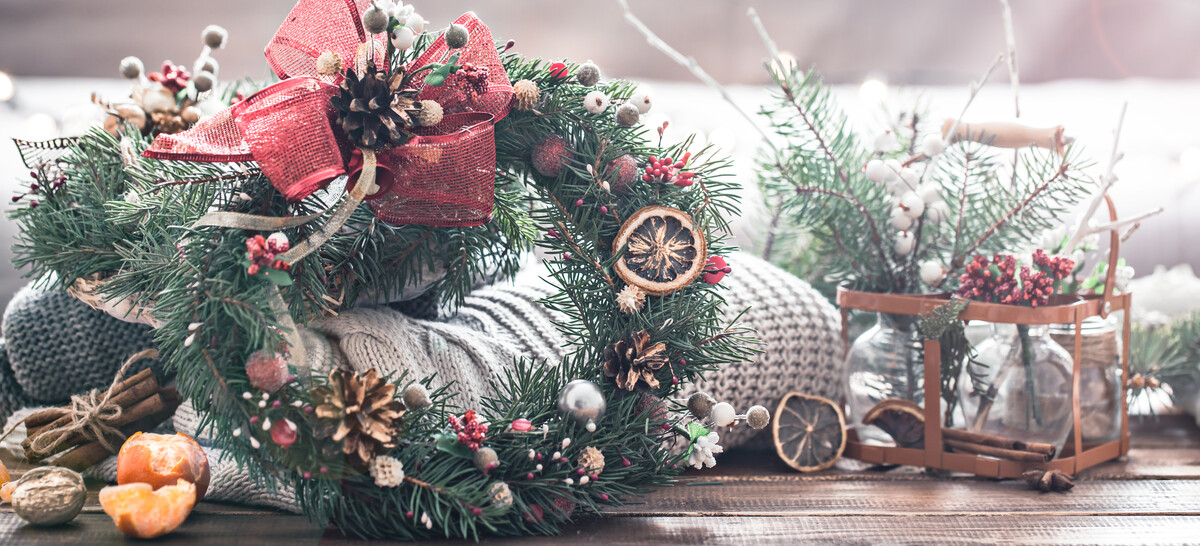 Christmas still life of a live Christmas tree, decorations and festive wreath on a background of knitted clothes and Mandarin